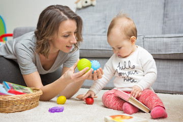 nine months old baby girl playing with her mother on the floor