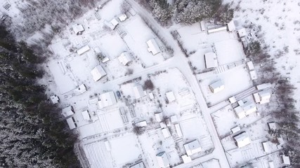 Wall Mural - Top view at Russian village in wild wintry forest. Snow covered roofs of frozen houses and courtyards. Karelia, Russia
