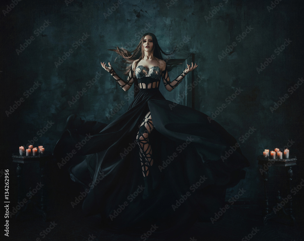 Beautiful witch floating in the air. Background dark room. Girl dressed in  a black dress with a long train. Stock Photo | Adobe Stock