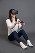 © Manuel - Young woman sitting and having fun playing a virtual reality vid