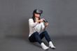 © Manuel - Young woman sitting and having fun playing a virtual reality vid