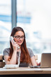 © Elnur - Young woman talking on phone in office
