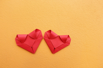 Poster - two folding red paper hearts on yellow concrete wall for pattern