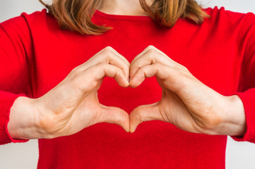 Female hands showing sign of heart on red