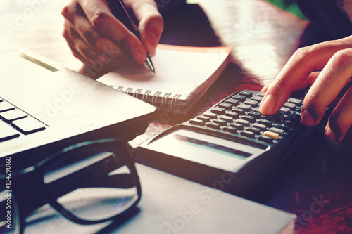Fotografía Close up woman hand using calculator and writing make note with