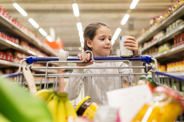 girl with food in shopping cart at grocery store