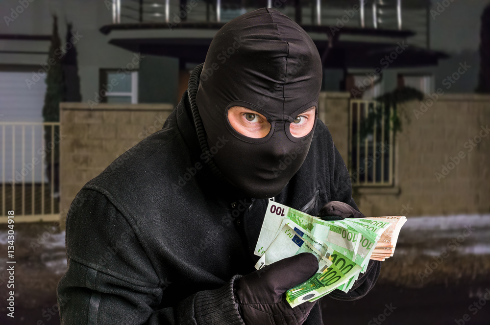Masked thief in balaclava with stolen money Stock Photo | Adobe Stock