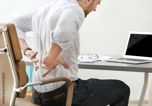 Cuadros en Lienzo Young man suffering from backache in office, closeup