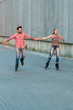 Man and woman rollerblading. Couple smiling and holding hands. Good impressions and cheerful mood.