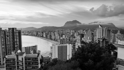 Sticker - Aerial view of summer resort Benidorm, Spain with beach and famous skyscrapers at sunset. City has three major beaches of the maximum quality standard. Time-lapse, fast pacing sky. Black and white