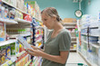 © Michael Traitov  - Young caucasian woman is watching into product composition and studying ingredients for healthy lifestyle. Woman is shopping in grocery store.