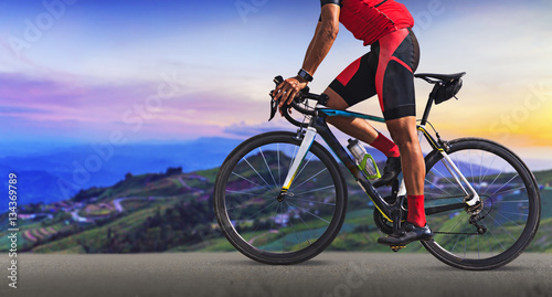 Plakat Mężczyzna na bicyklu na drodze między pięknymi górami
