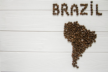  Map of the Brazil made of roasted coffee beans laying on white wooden textured background . Space for text