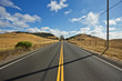 © Erickson Stock - Empty highway through a rural landscape against cloudy sky