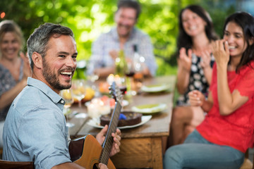 Wall Mural - Summertime, man playing guitar for his friends on a terrace