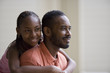 © Erickson Stock - Smiling teenage girl standing behind her father with her arms wrapped around him.