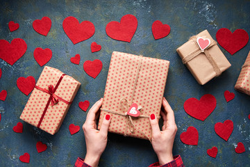 Wall Mural - Hands in the frame. Woman holding a gift for Valentine's Day or Birthday on a creative concrete background. Flat lay. Top view.