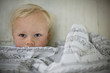 © Erickson Stock - Blond toddler peeking over the top of a blanket