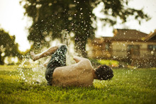 Young Man Lying On Grass And Enjoying Sprayed Water
