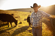 © Erickson Stock - Portrait of farmer standing on a field with cows in the background.