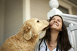 © Erickson Stock - Young female nurse playing with a dog on the verandah of someone's home.