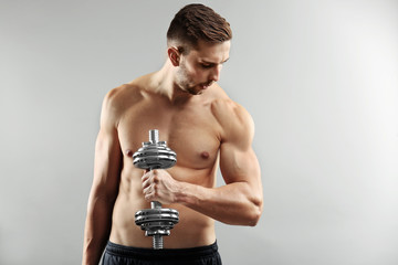 Sticker - Sporty man doing exercises with dumbbell on light background