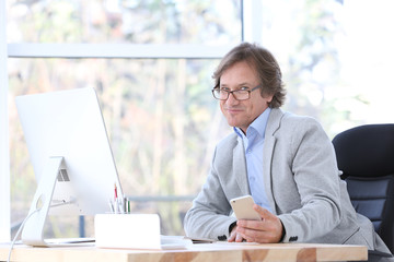 Canvas Print - Successful mature man with mobile phone in office