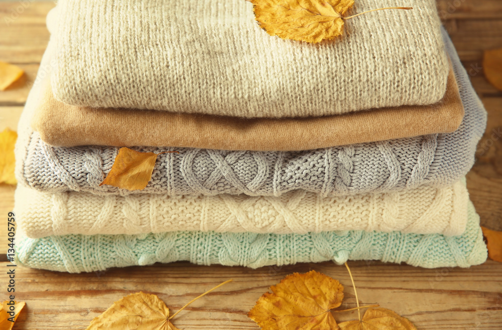 Stack of woolen clothes on wooden background, closeup