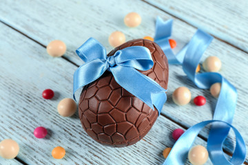 Sticker - Chocolate Easter egg with color ribbon bow on wooden background