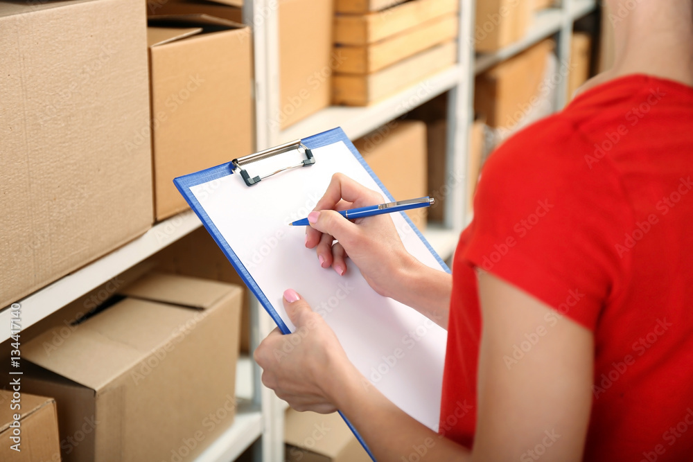 Young businesswoman with clipboard at warehouse
