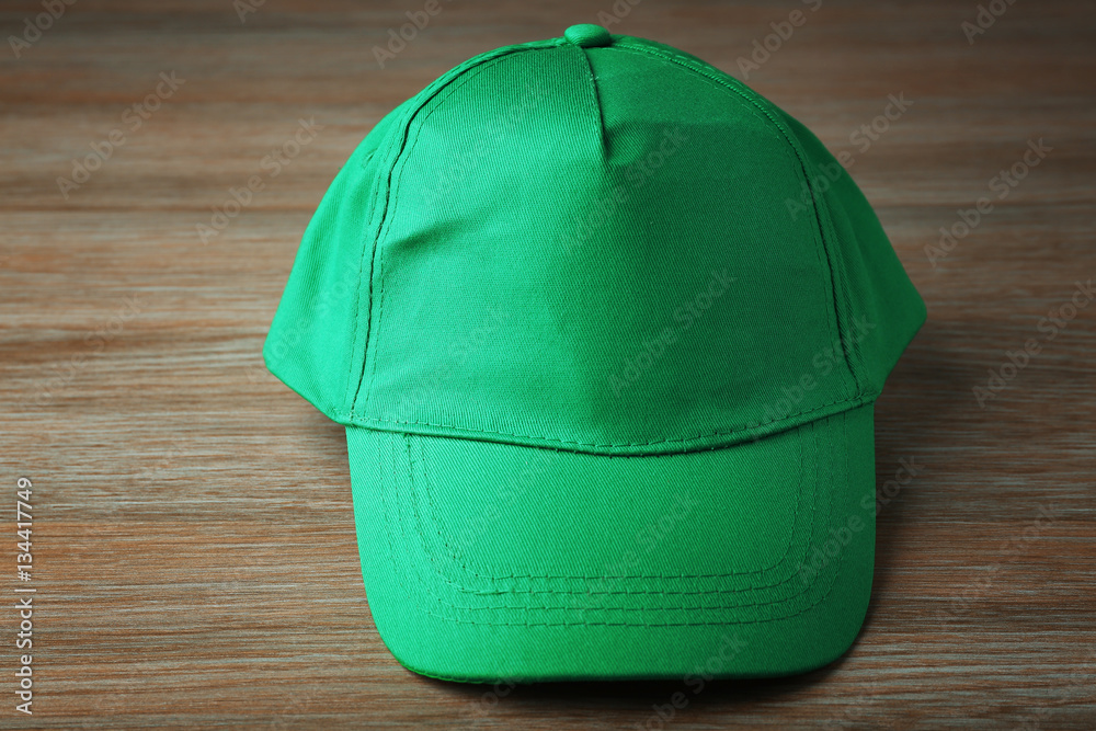 Blank green baseball cap on wooden background