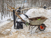 Shovel, Broom, And A Wheelbarrow Of Sand To Clean Snow From The Tracks In The Park.