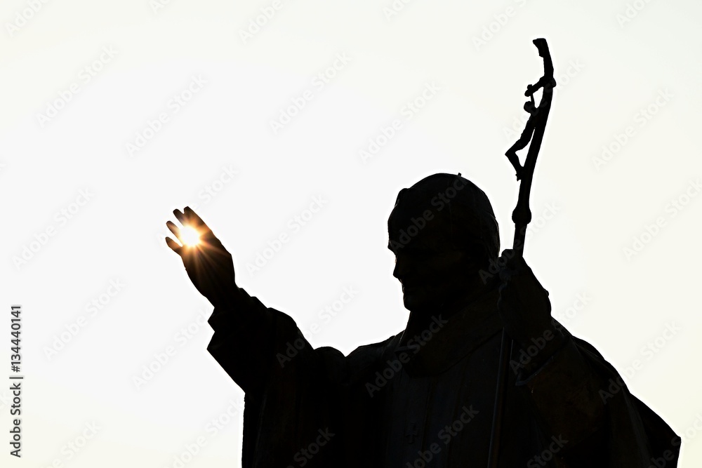 Silhouette of statue of pope John Paul The Second with afternoon sun in his palm, castle Nitra, Slovakia - obrazy, fototapety, plakaty 
