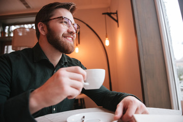 Poster - Cheerful bearded young man drinking coffee.