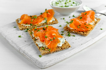 Wall Mural - Homemade Crispbread toast with Smoked Salmon, Melted Cheese and cress salad. on white wooden board