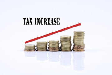 Conceptual image. Stacks of coins against white background with red arrow and TAX INCREASE words.