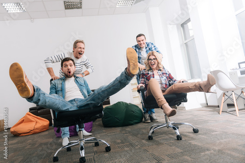 Poster Joyful happy people riding in the office chairs