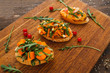 Tasty vegetarian canapes on wooden board. Tree portions of bruschetta with pumpkin and herbs. Recipe, healthy food, creative snack, seasonal snack concept
