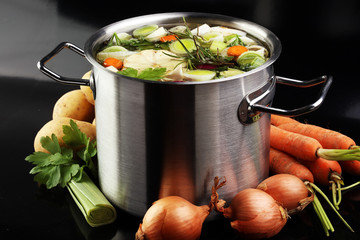 Broth with carrots, onions various fresh vegetables in a pot - c