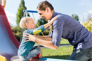 Wall Mural - Frau und kleiner Junge rutschen Rutsche runter auf Spielplatz