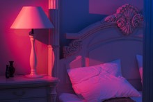 Luxurious Minimalistic Art Décor Bedroom With Royal Bed, Pink And Blue Light With Stylish Night Lamp At The Wooden Table 