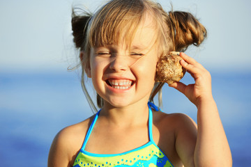 Canvas Print - Cute girl listening to seashell at sea