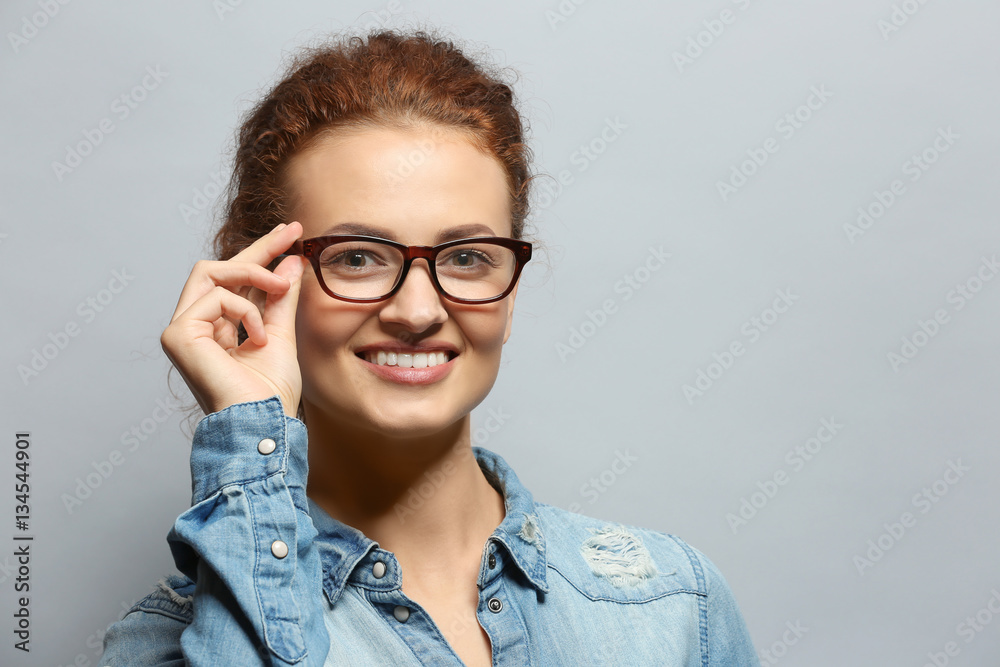Young woman with spectacles on grey background