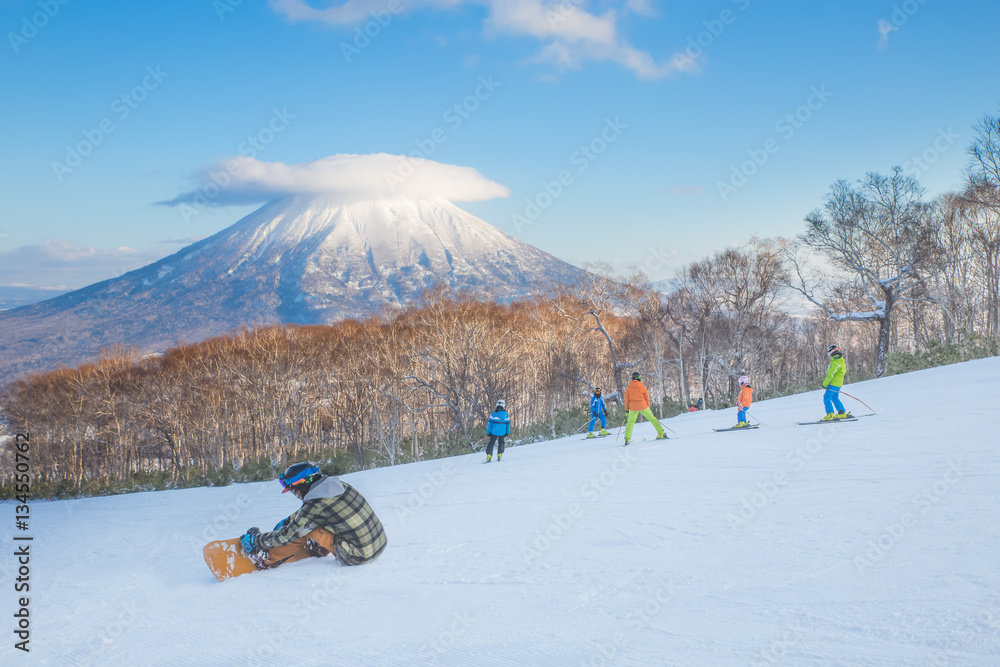 People skiing on the snow slope and Mt.Yotei as a background in Niseko Ski area, Hokkaido, Japan - obrazy, fototapety, plakaty 