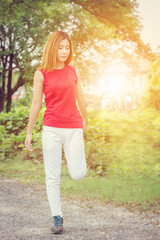 Portrait of young beautiful sporty woman stretching leg for warm