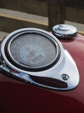 Close Up Of Motorcycle Detail With Chrome Speedometer And Gasoline Tank On Red Backgrounds
