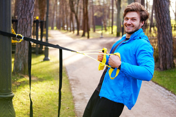 Wall Mural - A man exercising in a park with trx fitness strips.