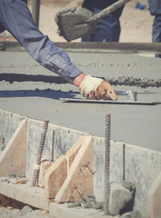 Construction worker leveling concrete pavement.