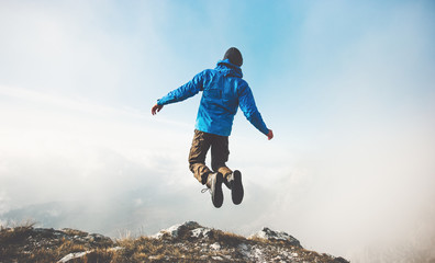 happy man jumping on mountains cliff to clouds sky lifestyle travel emotional success concept advent