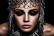 High fashion beauty model with metallic headwear and dark makeup and blue eyes on black background